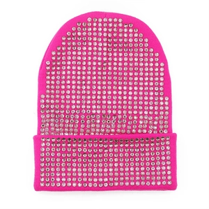 Dettaglio macro di un berretto in maglia rosa acceso con strass scintillanti per l'inverno
