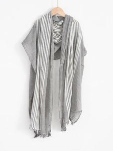 Detail of grey and white striped scarf with fringe hanging on wooden hanger