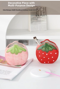 Close-up of pink and red strawberry ceramic holders for makeup brushes and stationery