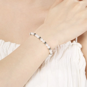 Detail eines Perlenarmbands mit Silberperlen am Handgelenk vor weißem Stoffhintergrund