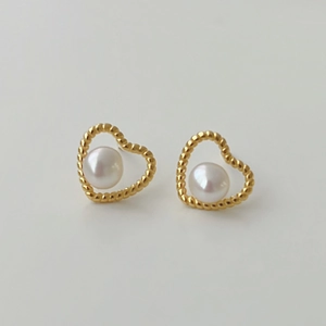 Close-up of golden hollow heart earrings with 925 silver and freshwater pearl detail