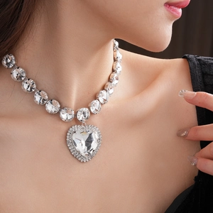 Detail of a large silver heart crystal necklace worn by a model in luxury style