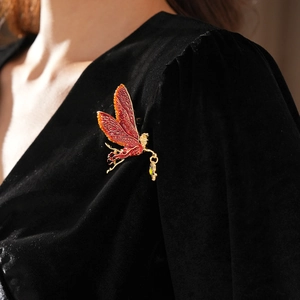 Close-up of vintage fairy brooch with enamel wings pinned on black velvet fabric