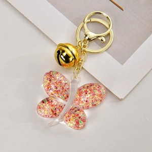Vue détaillée du porte-clés papillon rose avec paillettes, perles et clochette dorée
