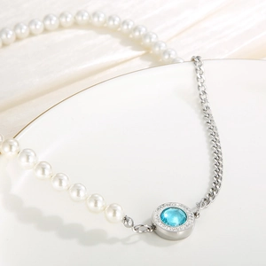 Close-up of split necklace featuring white pearls, silver Cuban chain, and blue zircon pendant
