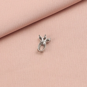 Close-up of a silver leaf-shaped pendant base for DIY jewelry on pink fabric