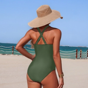 Back view of army green one-piece swimsuit with crisscross straps on a sunny beach