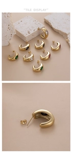 Detail view of C-shaped gold-plated earrings with colorful zircon stone inlay