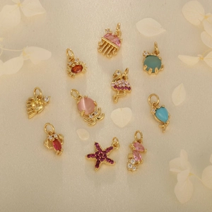 Collection of ten gold marine animal pendants with colorful zircons on white fabric