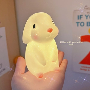 Close-up of a glowing rabbit night light with a sparkling finish held in a hand