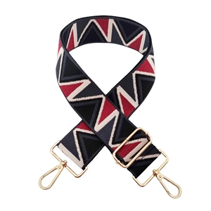 Close-up of wide woven shoulder strap with red and blue geometric zigzag patterns and gold hooks
