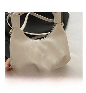 Detailed macro view of white pleated hobo bag texture with golden metallic buckle
