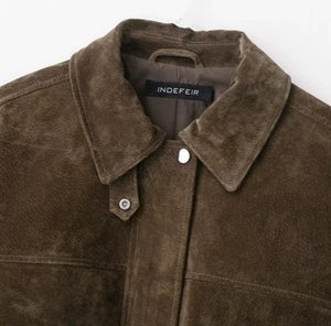 Close-up of the dark brown suede bomber jacket collar with interior brand label details