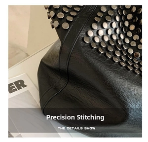 Close-up of black leather tote bag featuring silver rivet studs and precise stitching