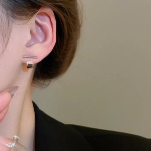 Detail of silver bar stud earrings and small metal hoops worn on the earlobe