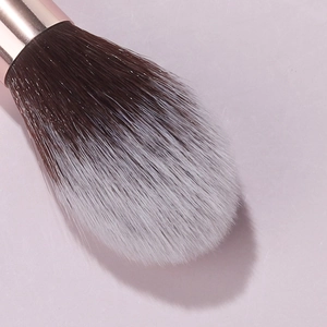 Close-up of dual-tone synthetic fiber makeup brush head with elegant rose gold ferrule