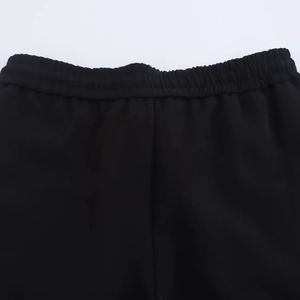 Detail of black sports trousers featuring an elastic waistband on a white background