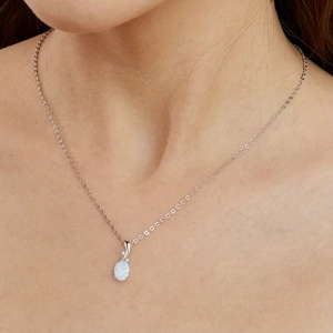 Elegant silver necklace featuring an oval opal pendant with sparkling accents on model
