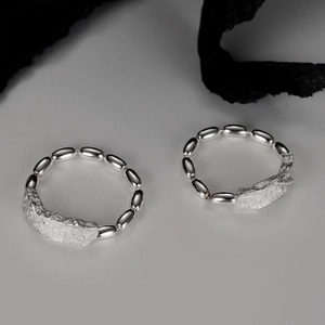 Detail view of two S925 sterling silver triple-layer twisted rings with irregular texture