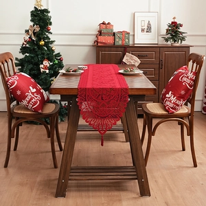 Red lace Christmas table runner with tassels and hollow floral patterns in a festive setting