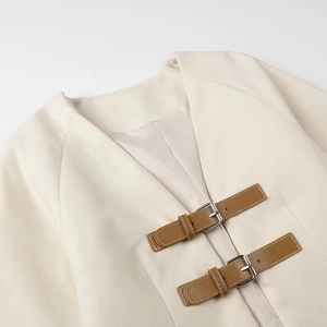 Detailed view of cream soft jacket featuring brown leather strap buckles and silver hardware
