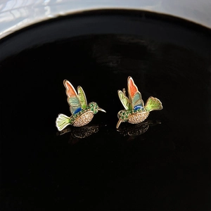 Detailed macro view of hummingbird stud earrings with colorful enamel and zircon stones