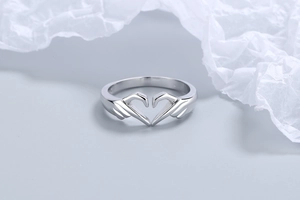 Close-up of a silver metal ring featuring a creative heart gesture hand-shaped design