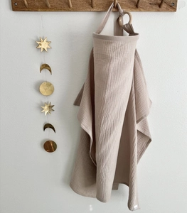 Detail of beige double-layer cotton nursing cover hanging on a wooden wall hook