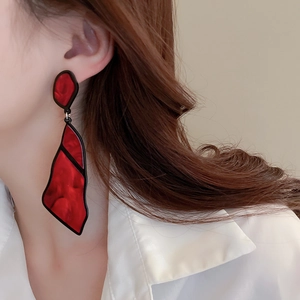 Close-up of red and black geometric acrylic drop earrings worn by a female model