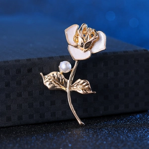 Detailed close-up of a gold rose brooch with white enamel petals and a pearl accent