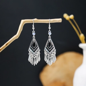 Detail view of Bohemian tassel earrings with black stones hanging on a natural branch