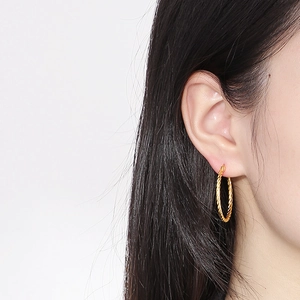 Detailed close-up of a 18k gold-plated twisted rope hoop earring worn by a model