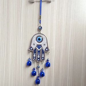Close-up of Hamsa Hand wall hanging with blue Evil Eye design and small metal bells