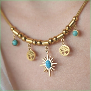 Detail of bohemian gold tree of life necklace with turquoise beads worn by a model