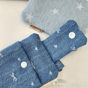 Detailed texture of denim card holders with star and bow patterns and metal zippers