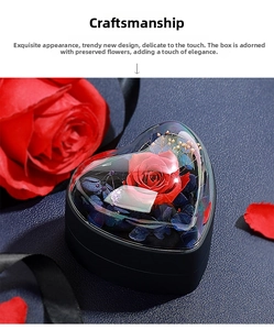 Boîte à bijoux en forme de cœur avec une rose éternelle rouge sous un dôme transparent.