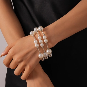 Gros plan d'un bracelet de perles à trois couches avec maillons argentés au poignet
