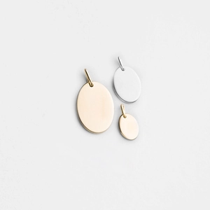 Detailed view of polished oval stainless steel pendants in gold and silver for jewelry DIY