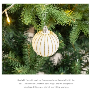 Weiße Weihnachtskugel mit goldenen Glitzerstreifen an einem grünen Weihnachtsbaum