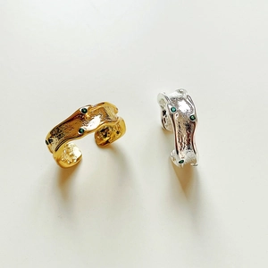 Close-up of irregular hammered silver rings in gold and silver with green gemstones