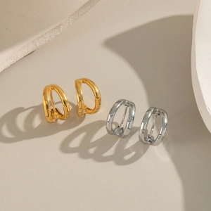 Macro detail of high-polished gold and silver double C-shaped hoop earrings with hinges