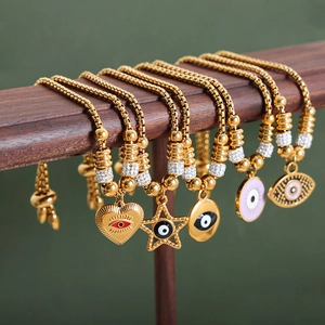 Adjustable golden evil eye bracelets with heart and star charms on a red stand