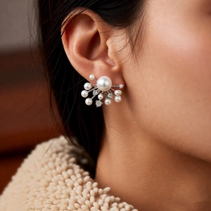 Close-up of elegant firework shaped pearl and zircon earrings worn by a model