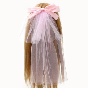 Elegant pink satin bow hair clip with white layered tulle veil on blonde hair