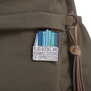 Close-up of Read Books enamel pin with colorful spines on olive green canvas bag