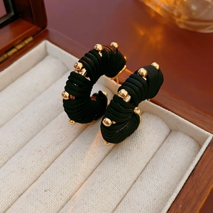Close-up of black and gold striped faux leather earrings in a beige velvet jewelry box