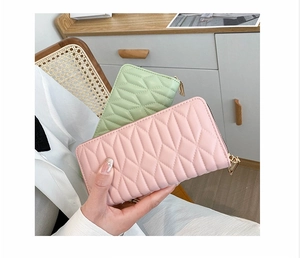 Detail of quilted PU leather long wallets in pink and green with gold zipper closures