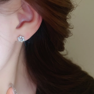 Close-up of minimalist silver snowflake earrings with sparkling zircons on earlobe