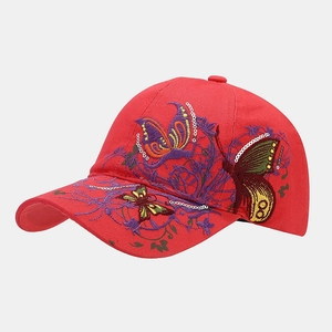 Detail of red baseball cap featuring colorful butterfly embroidery and sparkling sequins
