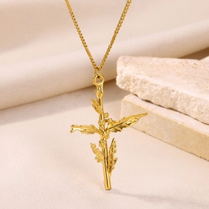 Close-up of gold-plated 3D floral cross pendant on textured stone background